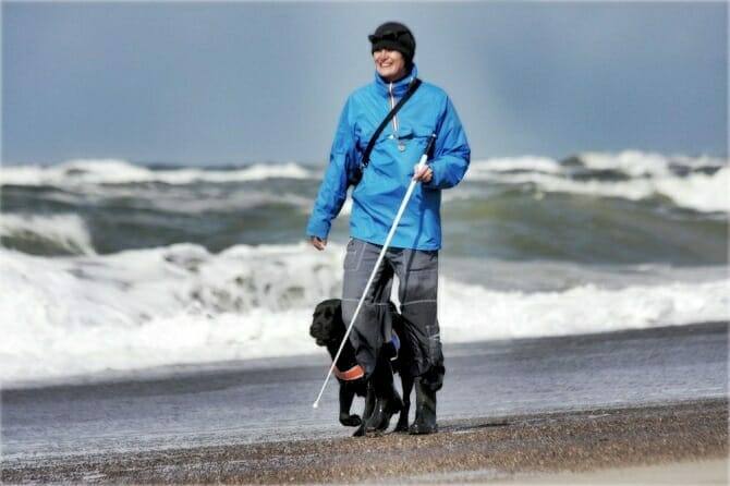 Assistenzhundetrainer Ausbildung - Spaziergang am Strand blinde Frau mit Hund