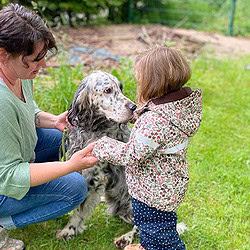 ATN Therapiebegleithundetrainer Ausbildung - Frau kniet neben Kind und Hund und hält Hand des Mädchens