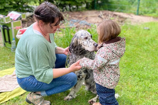ATN Therapiebegleithundetrainer Ausbildung - Frau kniet neben Kind und Hund und hält Hand des Mädchens