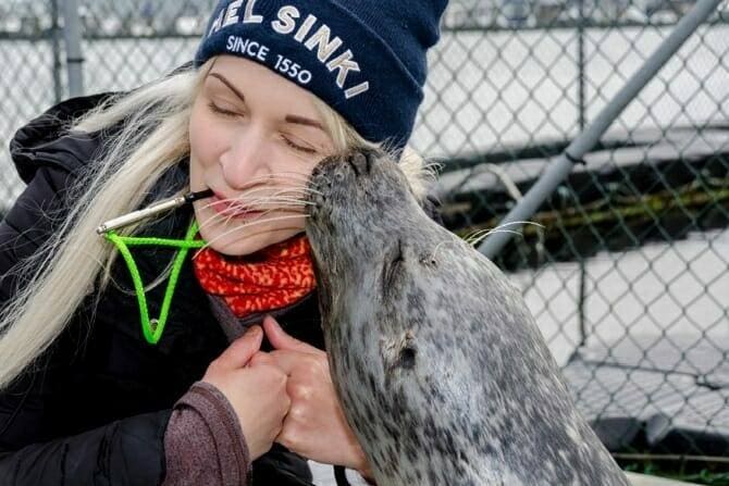 Tiertrainer Ausbildung - blonde Frau wird von Robbe geküsst