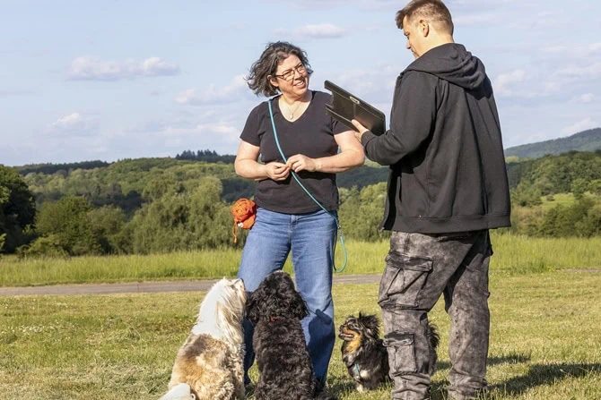 ATN Hundetrainer Ausbildung - Hundetrainer mit Kundin und Hunden auf der Wiese